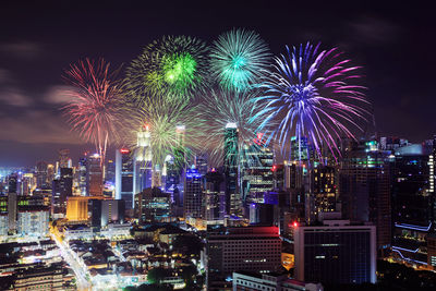 Firework display over illuminated buildings in city at night