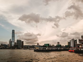 Buildings by river against sky in city