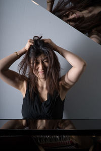 Portrait of woman with hands in hair at home