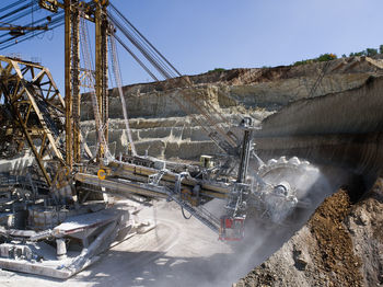 Earth mover on mining mountain against clear sky