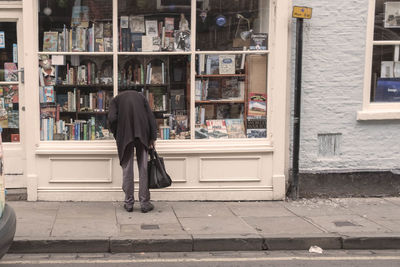 Rear view of woman walking on footpath against buildings in city