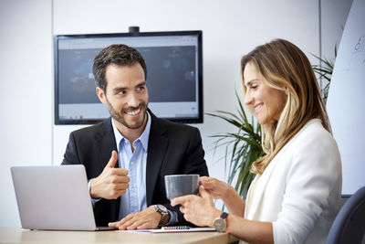 Woman using phone while sitting on table