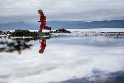 Girl running on beach reflection water and sky