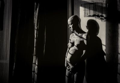 Full length of shirtless man and woman standing on mirror