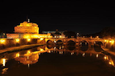 Illuminated bridge over river at night