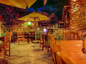 Empty chairs and tables at sidewalk cafe at night