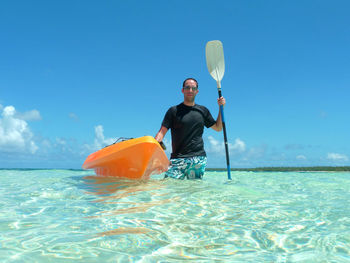 Portrait of man with kayak and oar in sea against sky