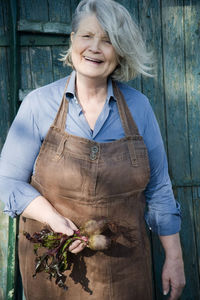 Senior woman harvesting beetroot, garden apron made of old linen pants