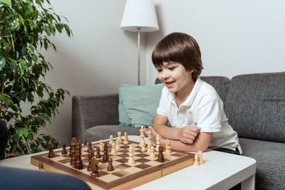 Little happy curious child playing chess with dad at home in living room. childhood hobby  leisure