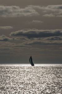 Boat sailing in sea against cloudy sky