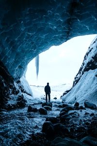 Rear view of man standing in sea during winter