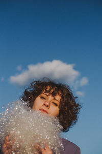 Portrait of woman with plastic against blue sky
