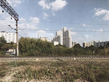 Plants growing on field by buildings against sky