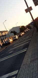 Cars on street in city against sky at sunset