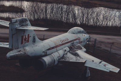 Side view of airplane on field by lake