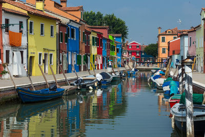 Boats moored in canal by buildings in city