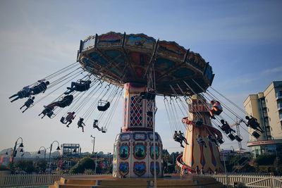 Low angle view of chain swing ride against sky