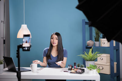 Portrait of young woman sitting on table