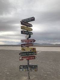 Information sign on beach against sky