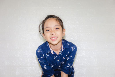 Portrait of smiling girl standing against wall