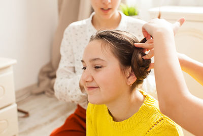 Sister making braids of sibling at home