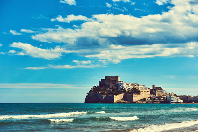 House by sea against cloudy sky