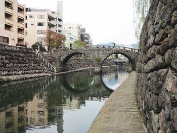 Bridge over river in city against sky