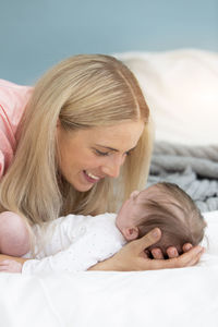 Mother kissing baby girl on bed at home