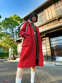 Full length of young woman standing against japanese house