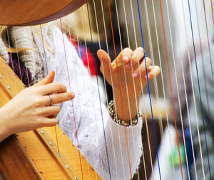 Midsection of woman playing harp