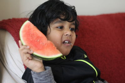 Close-up of cute boy holding watermelon at home