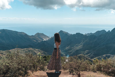 Rear view of woman looking at mountains against sky