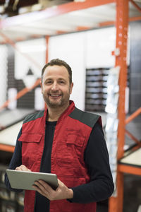 Portrait of happy salesman holding digital tablet while standing in hardware store