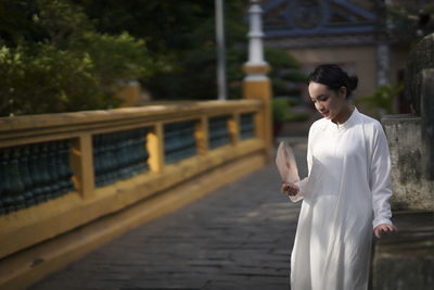 Side view of woman standing against white wall