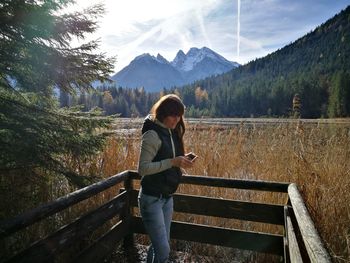 Full length of woman using mobile phone against sky