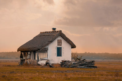 Abandoned house on field against sky during sunset