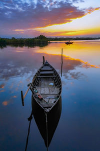 Boat moored on sea against sky during sunset