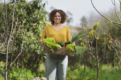 Woman holding umbrella while standing in basket against plants