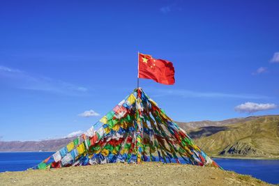 Multi colored flag on mountain against blue sky