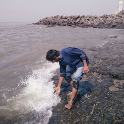 Full length of man standing in sea against sky