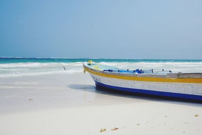 Boat moored on beach against sky