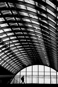 Low angle view of silhouette man walking on ceiling