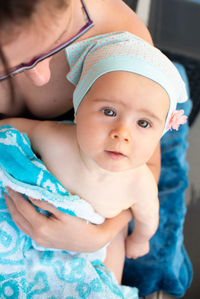 Mother holding baby girl on lap, covered with towel after swimming. summer activities.