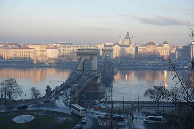 Bridge over river in city against cloudy sky