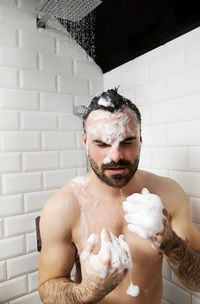 Shirtless man taking shower in bathroom