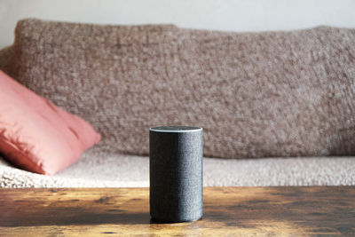 Close-up of smart speaker on table against sofa at home