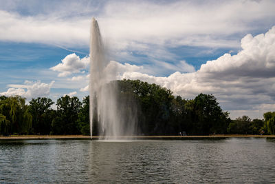 View of fountain in lake against cloudy sky