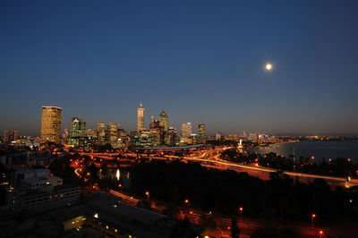 Illuminated cityscape against sky at dusk