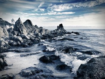 Rocky shore by sea against sky