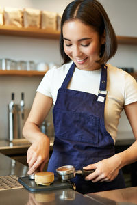 Portrait of young woman preparing food at table